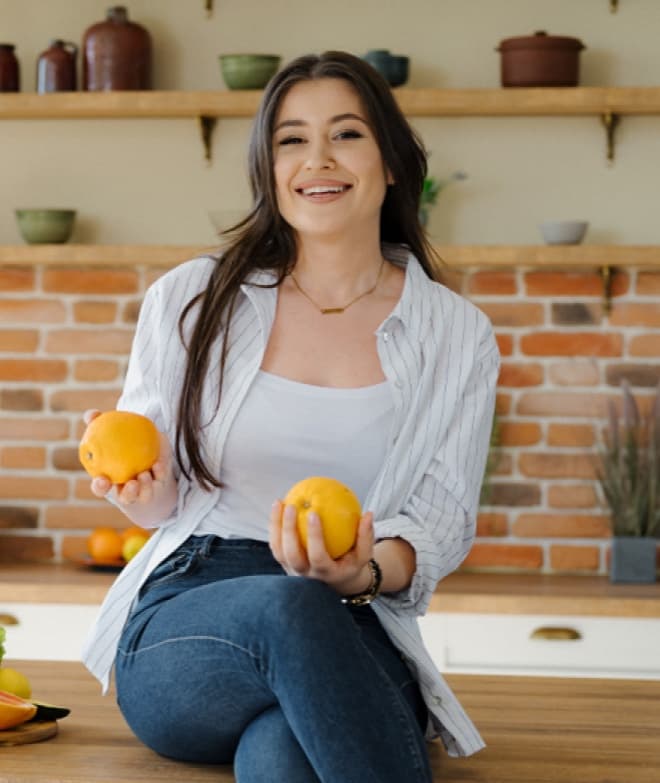 Tatiana smiling in her kitchen, holding fresh oranges